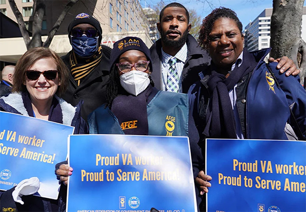 AFGE members pose for a group picture with signs that read, 