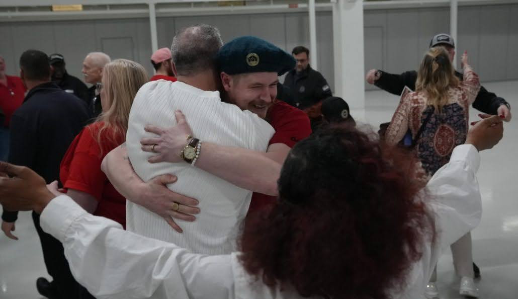 Workers shown celebrating and hugging.