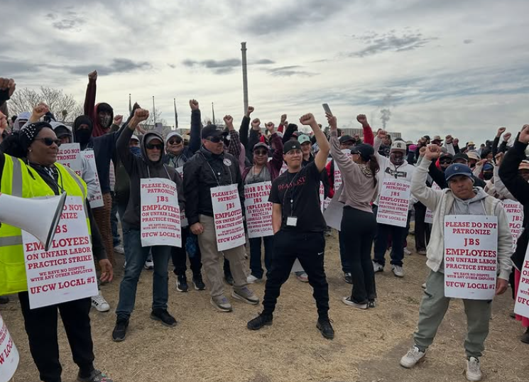 UFCW members on the picket line, raising their fists in solidarity.