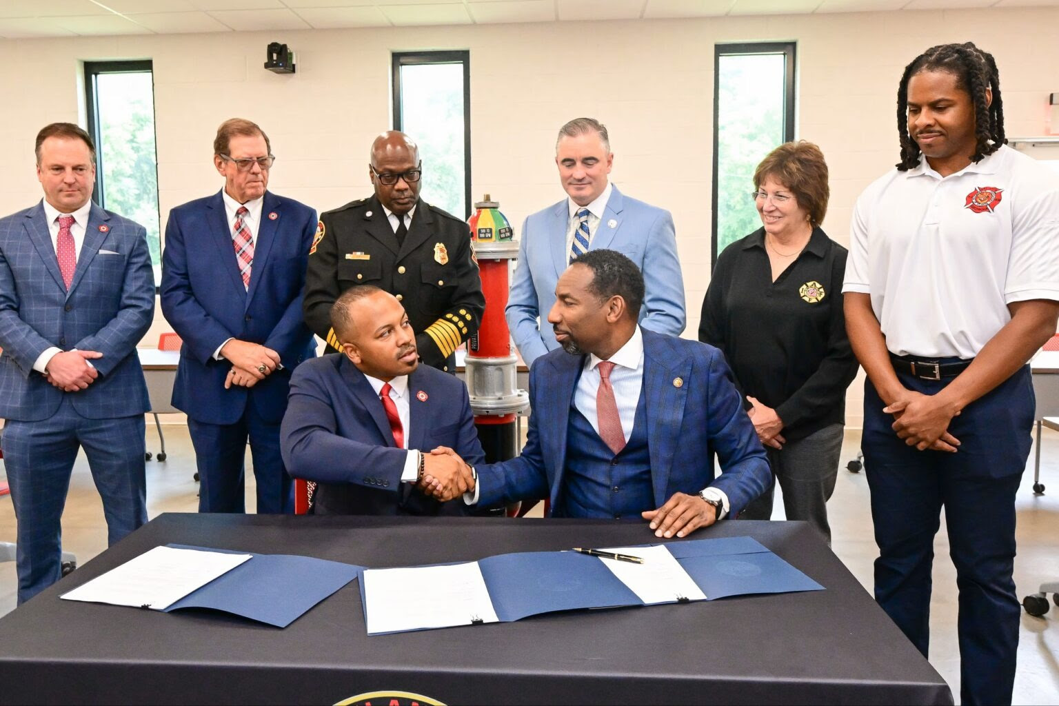 Alvin Rashad [left] and Atlanta Mayor Andre Dickens shake hands as IAFF General President Edward Kelly looks on [back row, third from right].