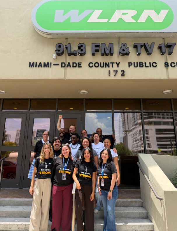 SAG-AFTRA members pose for a group picture in front of WLRN.