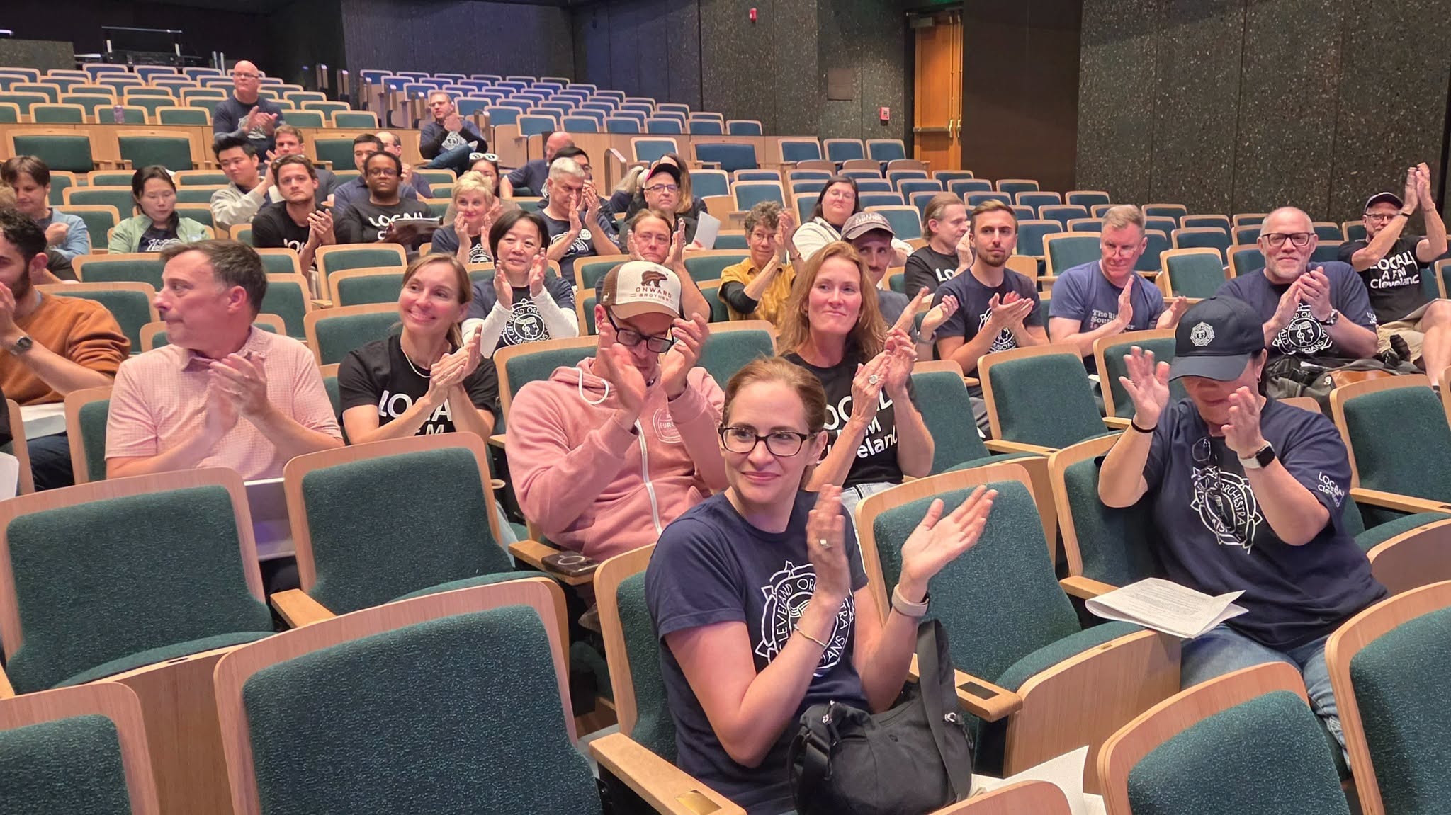 AFM members applaud while seated in an auditorium.