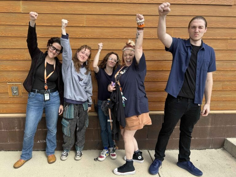 Workers pose for a group picture with fists raised in solidarity.
